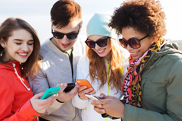 Image showing smiling friends with smartphones