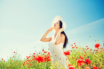 Image showing smiling young woman in straw hat on poppy field