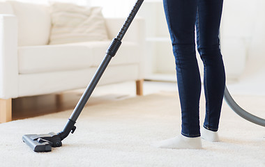 Image showing close up of woman legs with vacuum cleaner at home