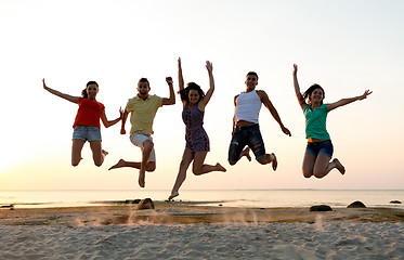 Image showing smiling friends dancing and jumping on beach