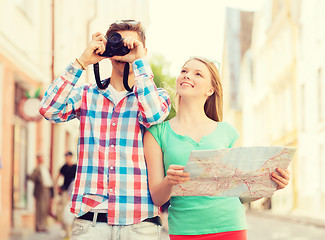 Image showing smiling couple with map and photo camera in city