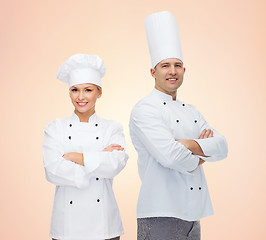 Image showing happy chefs or cooks couple over beige background