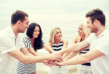 Image showing smiling friends putting hands on top of each other