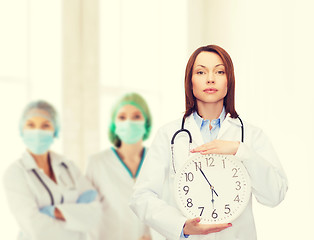 Image showing calm female doctor with wall clock