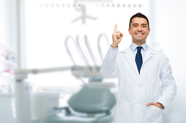 Image showing smiling male dentist pointing finger up