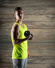 Image showing young man with dumbbell flexing biceps