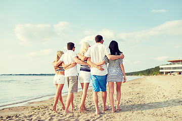Image showing smiling friends hugging and walking on beach