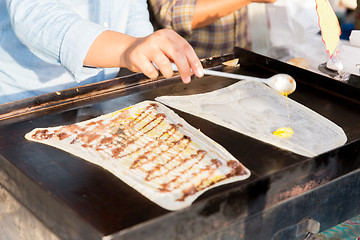 Image showing close up of cook frying pancakes at street market