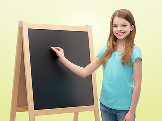 Image showing happy little girl with blackboard and chalk