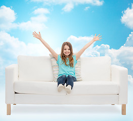 Image showing happy girl sitting on sofa with raised hands