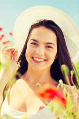 Image showing smiling young woman in straw hat on poppy field