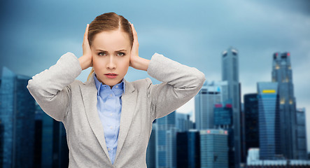 Image showing stressed businesswoman with covered ears