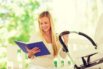 Image showing happy mother with book and stroller in park