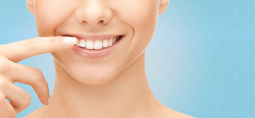 Image showing close up of smiling woman face pointing to teeth