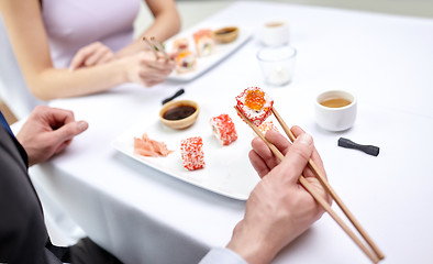 Image showing close up of couple eating sushi at restaurant