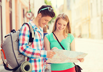 Image showing smiling couple with map and backpack in city