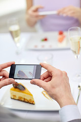 Image showing close up of couple with smartphones at restaurant