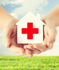 Image showing hands holding paper house with red cross