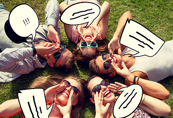 Image showing group of smiling friends lying on grass outdoors