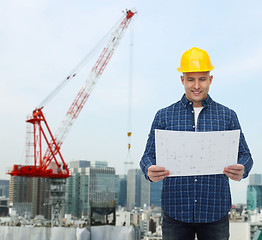 Image showing smiling male builder in helmet with blueprint