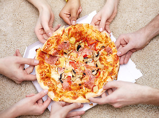 Image showing close up of happy friends eating pizza at home