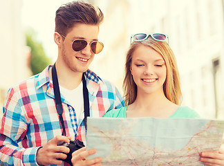 Image showing smiling couple with map and photo camera in city