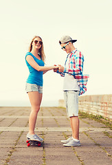 Image showing smiling couple with skateboard outdoors