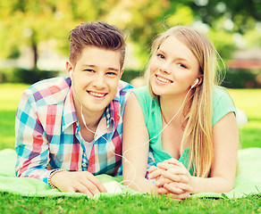 Image showing smiling couple with smartphone and earphones