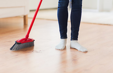 Image showing close up of woman legs with broom sweeping floor