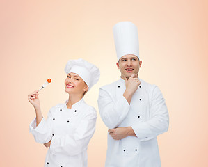 Image showing happy chefs or cooks couple over beige background