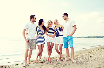 Image showing smiling friends in sunglasses talking on beach