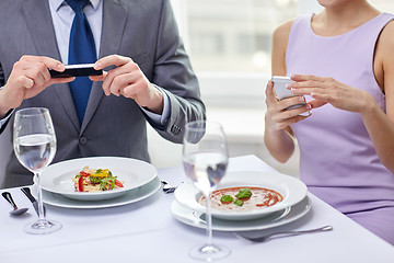 Image showing close up of couple with smartphones at restaurant