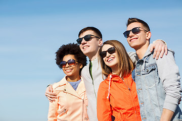 Image showing happy teenage friends in shades hugging outdoors