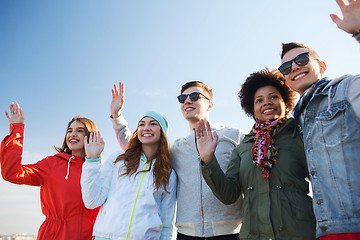 Image showing happy teenage friends in shades waving hands