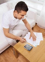 Image showing man with papers and calculator at home