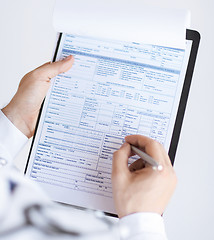 Image showing male doctor holding prescription paper in hand