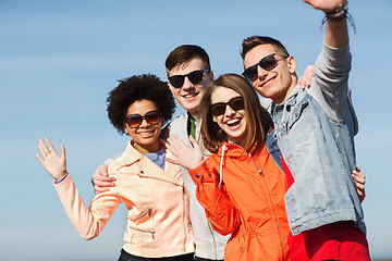 Image showing happy teenage friends in shades waving hands