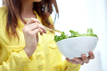 Image showing close up of young woman eating salad at home