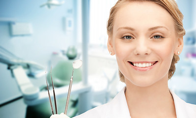 Image showing happy young female dentist with tools