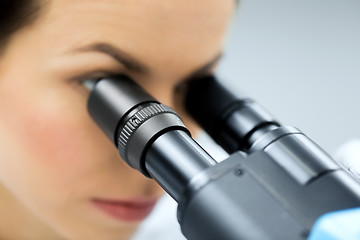 Image showing close up of scientist looking to microscope in lab