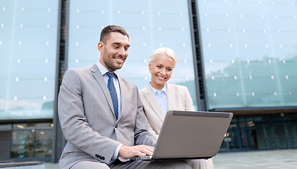 Image showing smiling businesspeople with laptop outdoors