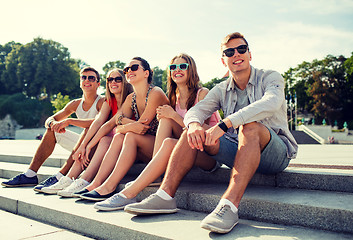 Image showing group of smiling friends sitting on city street