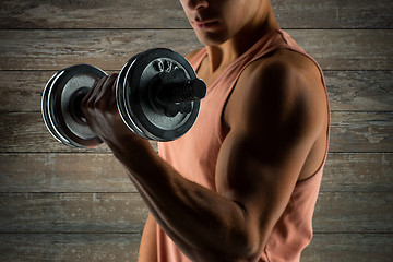 Image showing close up of young man with dumbbell flexing biceps