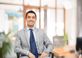 Image showing happy businessman sitting in office chair