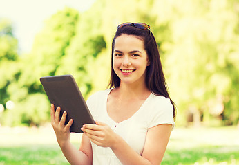 Image showing smiling young girl with tablet pc sitting on grass