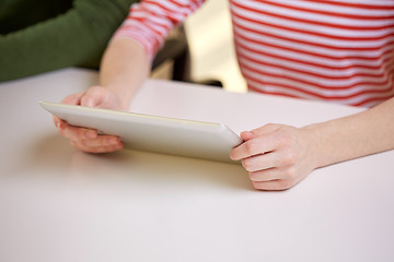 Image showing close up of female hands with tablet pc at table