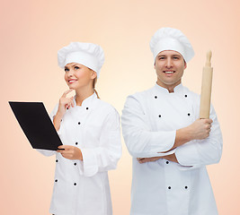 Image showing happy chefs or cooks couple holding rolling pin