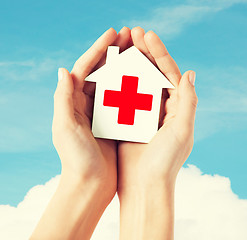 Image showing hands holding paper house with red cross