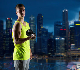 Image showing young man with dumbbell flexing biceps