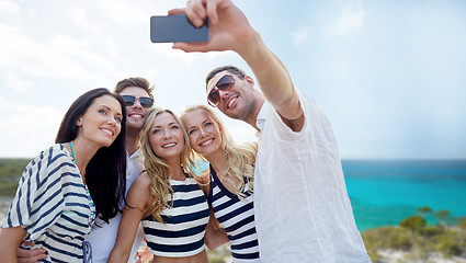 Image showing friends on beach taking selfie with smartphone